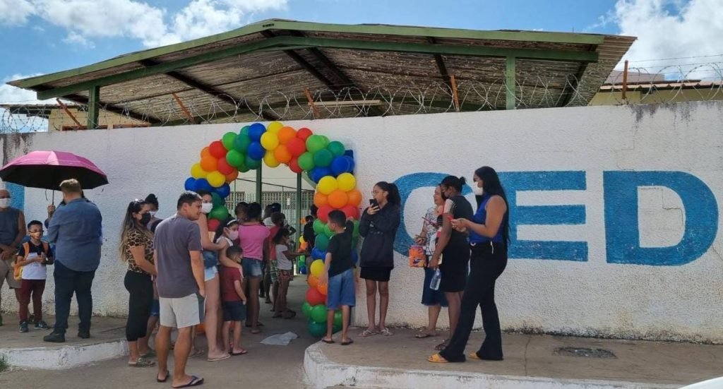 Balões e pessoas em frente a muro de escola