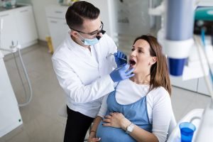Mulher grávida com dentista olhando sua boca