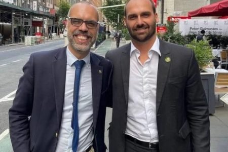 Allan dos Santos, ativista bolsonarista, tira foto sorrindo ao lado de Eduardo Bolsonaro em Nova Iorque. Ambos usam terno - Metrópoles