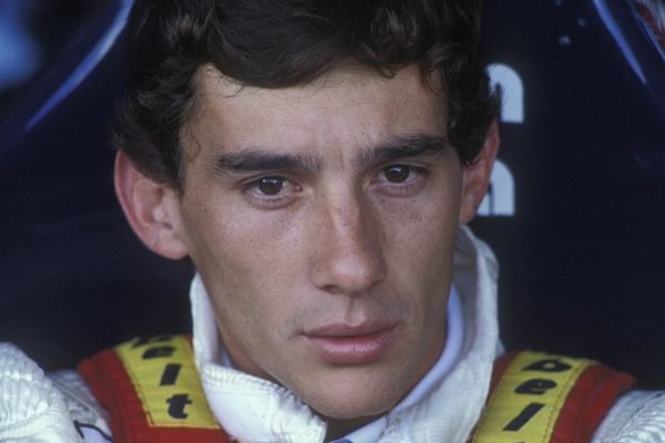 Considerado o maior piloto de Fórmula 1 do Brasil, Ayrton Senna hoje comemoraria 62 anos. Na foto ele olha sério para frente em uniforme de corrida - Metrópoles