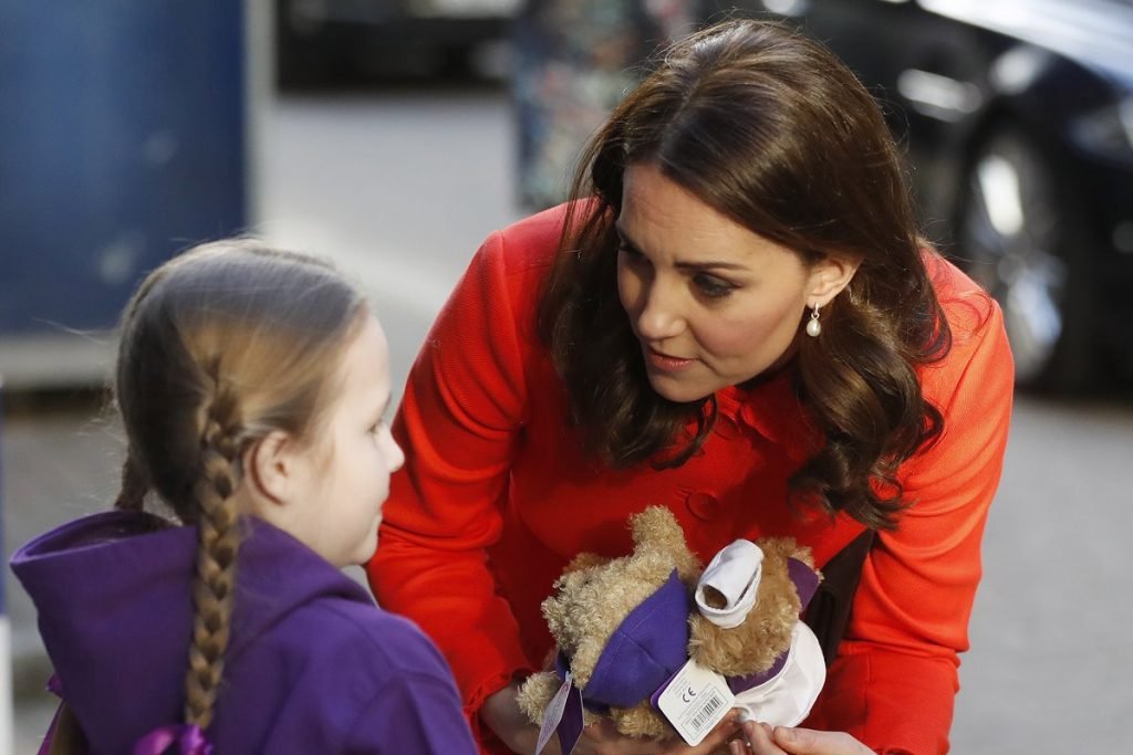 Foto colorida. Kate Middleton recebe um ursinho de uma menina