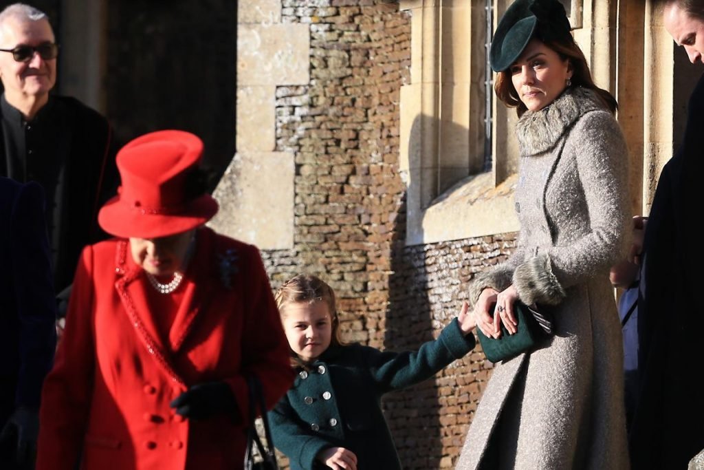 Foto colorida. Rainha Elizabeth, princesa Charlotte e Kate Middleton