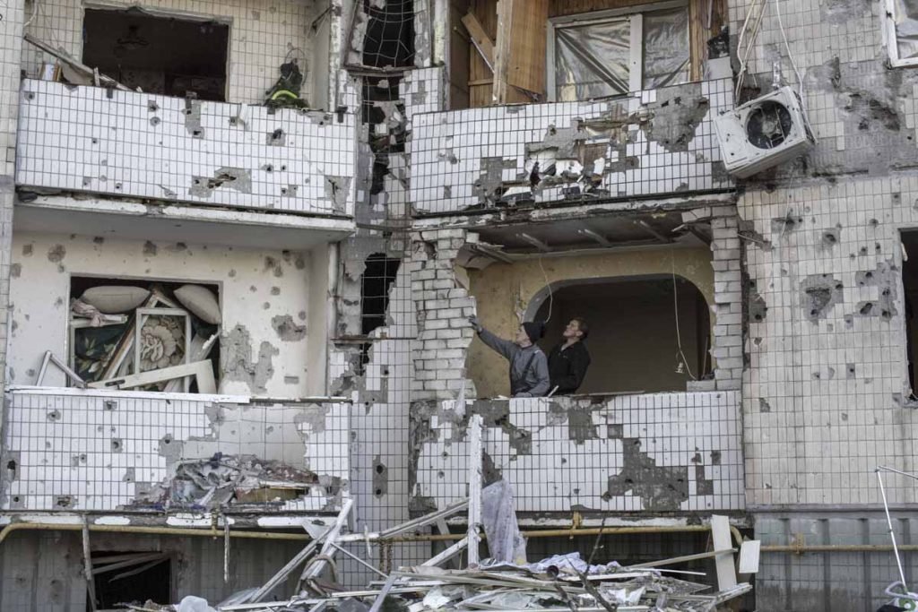 Dois civis examinam danos em estrutura da prédio residencial após ataque aéreo da Rússia em Kiev, Ucrânia - Metrópoles