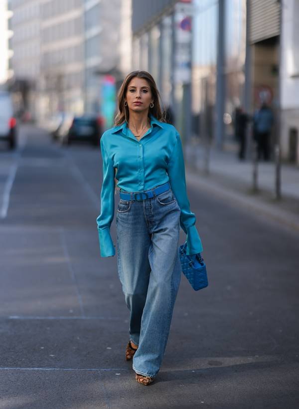 Look com camisa azul acetinada e calça jeansno street style