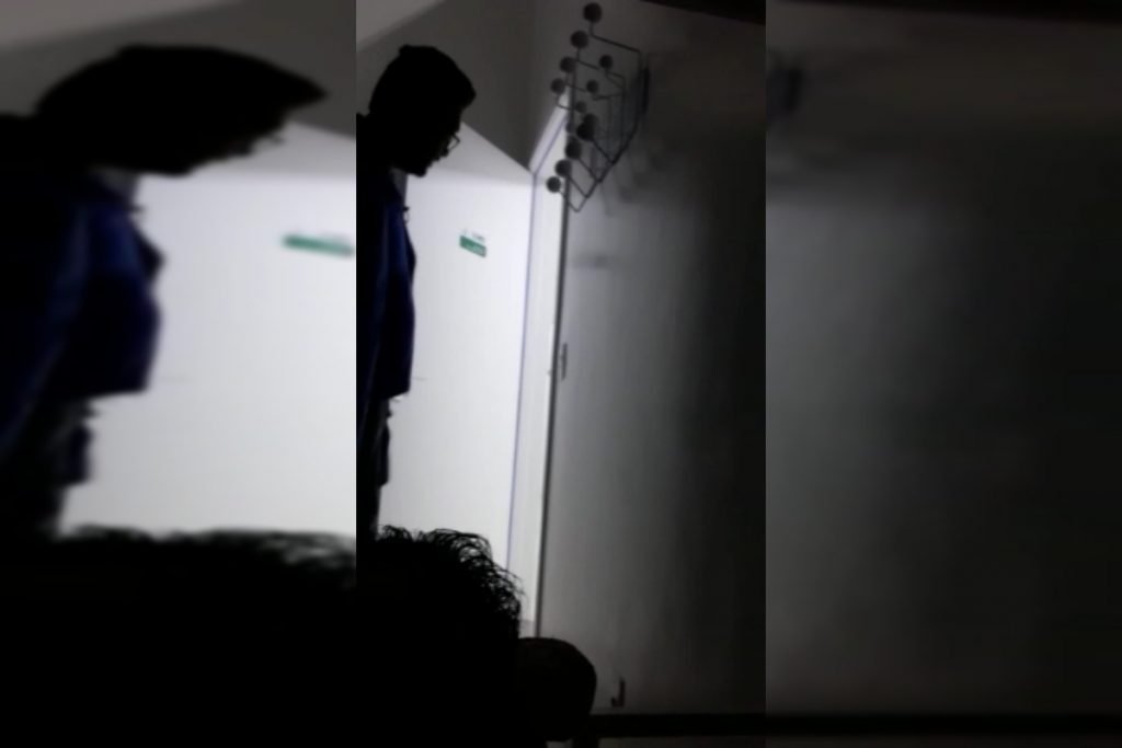 Homem parado perto da porta dentro de um quarto escuro