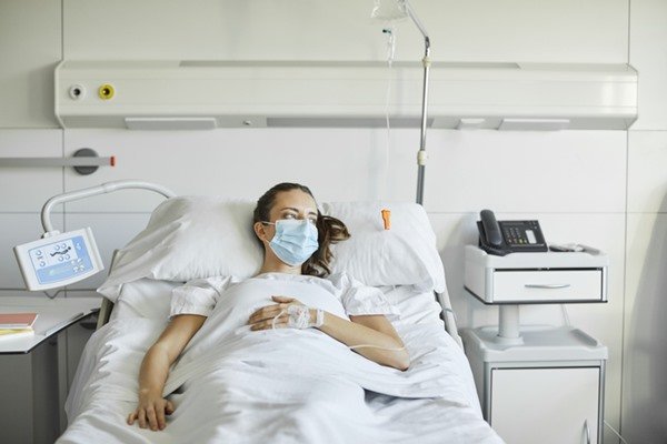 Mulher deitada em uma maca hospitalar - Metrópoles