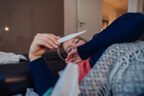 Person lying down looking at thermometer that indicates body temperature - Metropolis