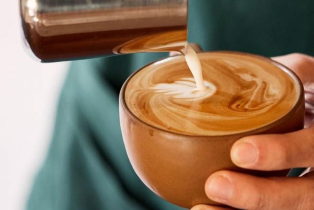 na foto temos uma pessoa fazendo uma latte art