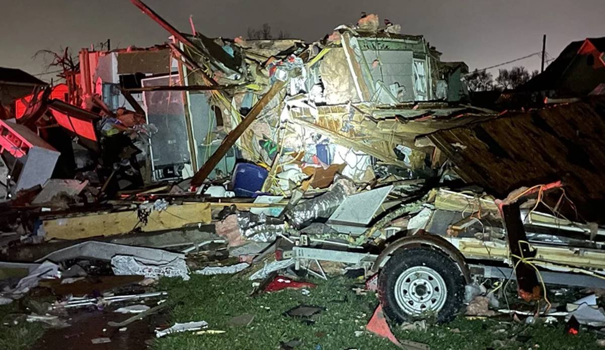 foto de um carro destruído e destroços de casas e outros objetos