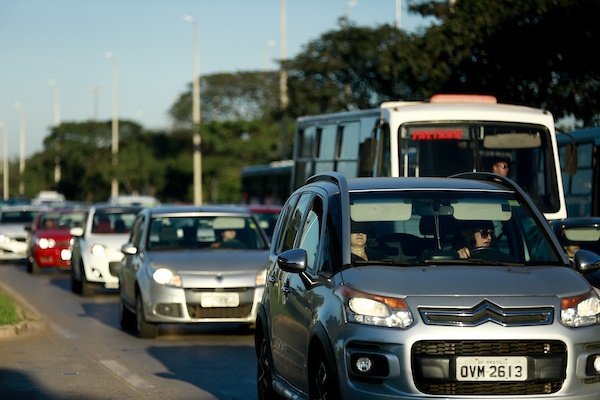 Foto colorida de carros e ônibus no trânsito