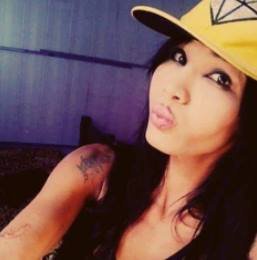 Travesti de boné amarelo e fazendo biquinho