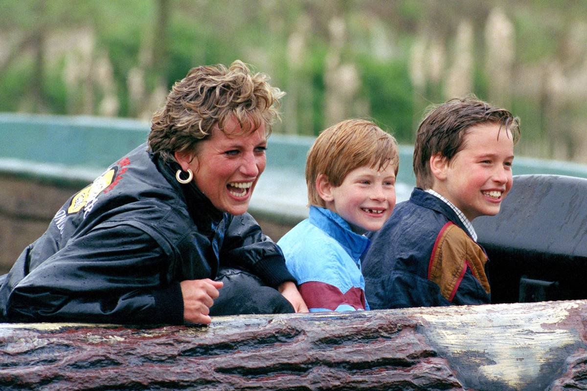 Foto colorida. Princesa Diana, príncipe Harry e príncipe William com roupas molhadas e sorridentes