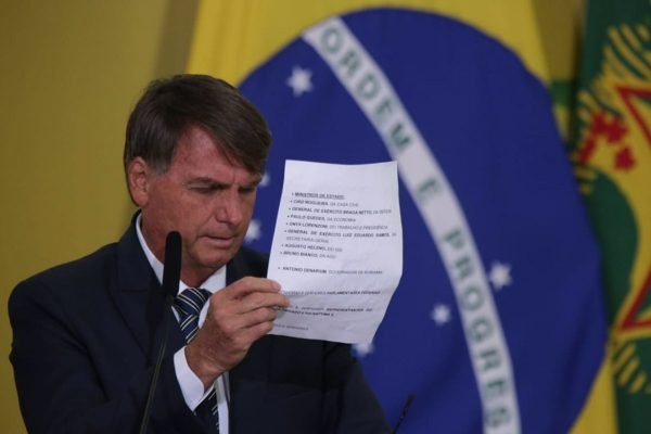 O presidente Bolsonaro lê discurso no Planalto no lançamento do Programa Renda e Oportunidade. Ele usa terno e segura folha de papel, frente ao microfone com a bandeira do Brasil ao fundo - Metrópoles