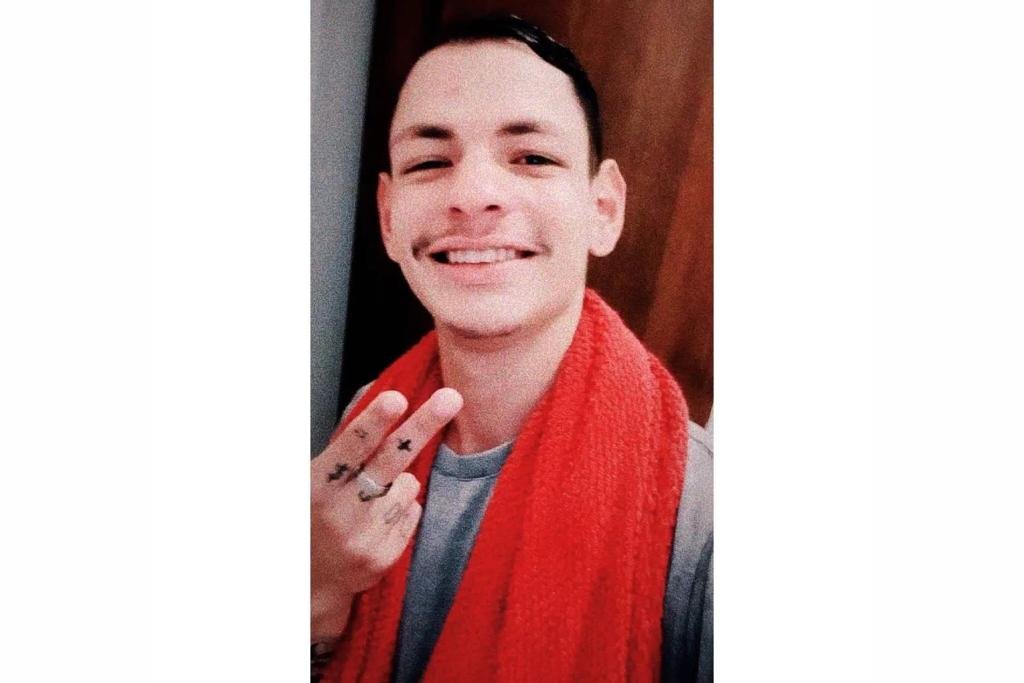 Jovem usando camiseta cinza. Ele tem tatuagens no braço e mão - Metrópoles