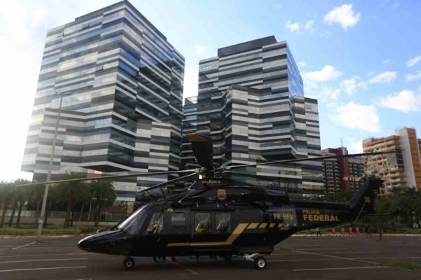 Veículos da PF se posicionam na frente do novo prédio da Polícia Federal para a inauguração da estrutura. Em destaque, um helicóptero da corporação - Metrópoles