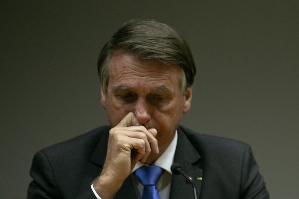 Presidente Bolsonaro coça o nariz em meio a fala. Ele usa terno e olha preocupado para baixo - Metrópoles