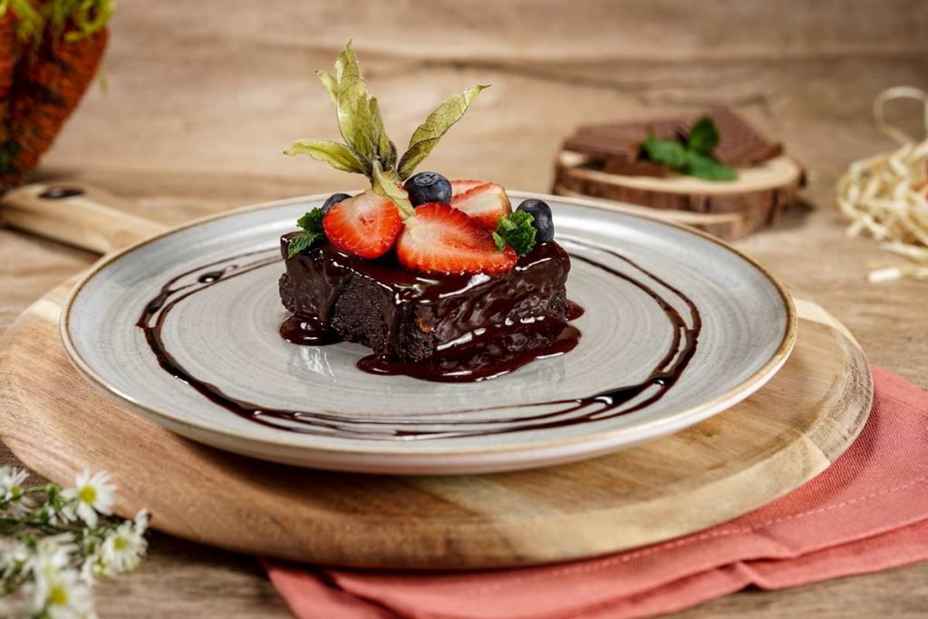 na foto temos um prato redondo com um brownie coberto de frutas vermelhas