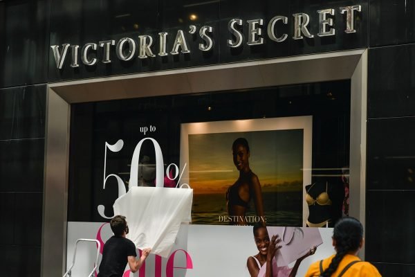 Homem branco colando adesivo em vitrine de loja