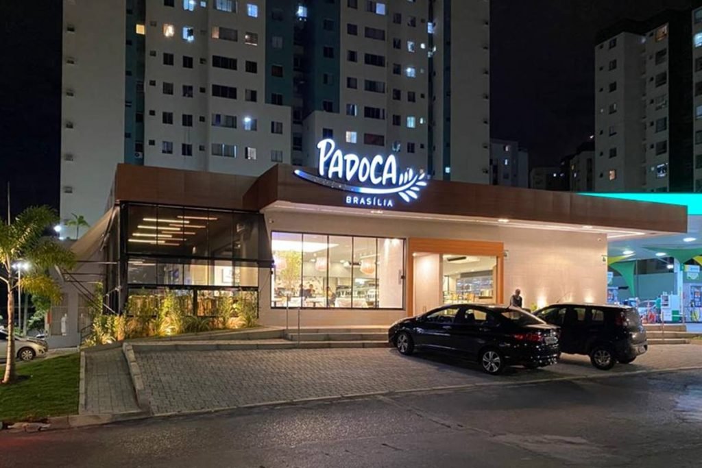 na foco vemos a fachada de uma padaria e atras predios