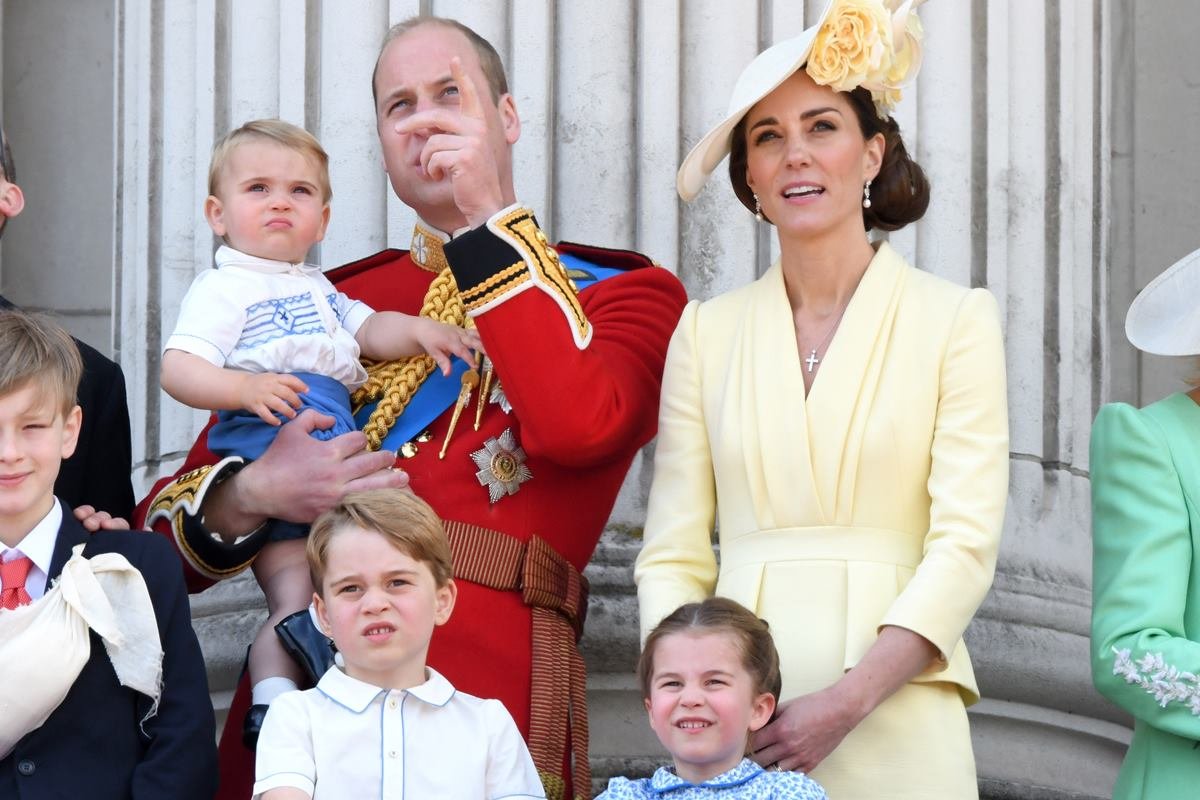 Foto colorida. Príncipe Louis, príncipe William, príncipe George, Kate Middleton e princesa Charlotte na varanda do Palácio de Buckingham