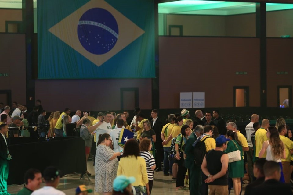 Bandeira do Brasil dentro de um auditório com uma multidão