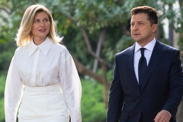 A primeira-dama da Ucrânia, Olena Zelenska, com roupas brancas ao lado do marido, o presidente Zelensky, de terno - Metrópoles