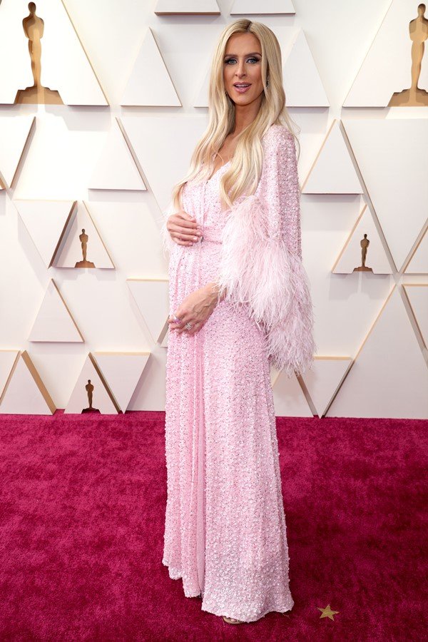 A socialite Nicky Hilton, irmã de Paris Hilton, no tapete vermelho do Oscar 2022. Ela usa um vestido rosa com penas.