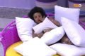 Natália Deodato, participante do BBB22, deitada entre travesseiros, desabafa com o participante Lucas Bissoli sobre sua relação com Jessi e Linn. Ela limpa o choro no rosto. Natália é negra, tem cabelo preto e crespo e tem vitiligo - Metrópoles