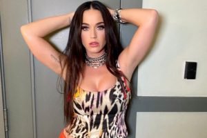 Foto colorida da cantora Katy Perry. Ela é uma mulher branca e está com cabelo castanho e mãos na cabeça - Metrópoles