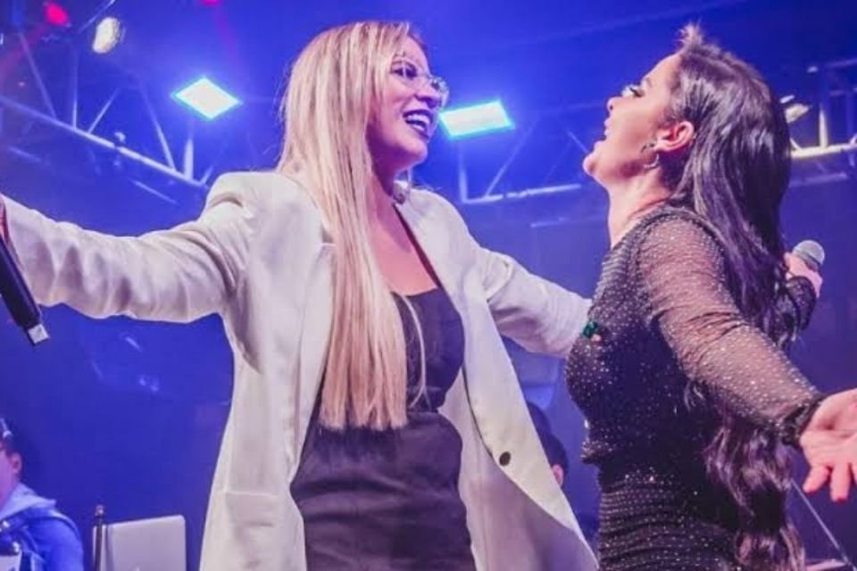 A foto colorida mostra Maiara e Marília Mendonça em cima do palco