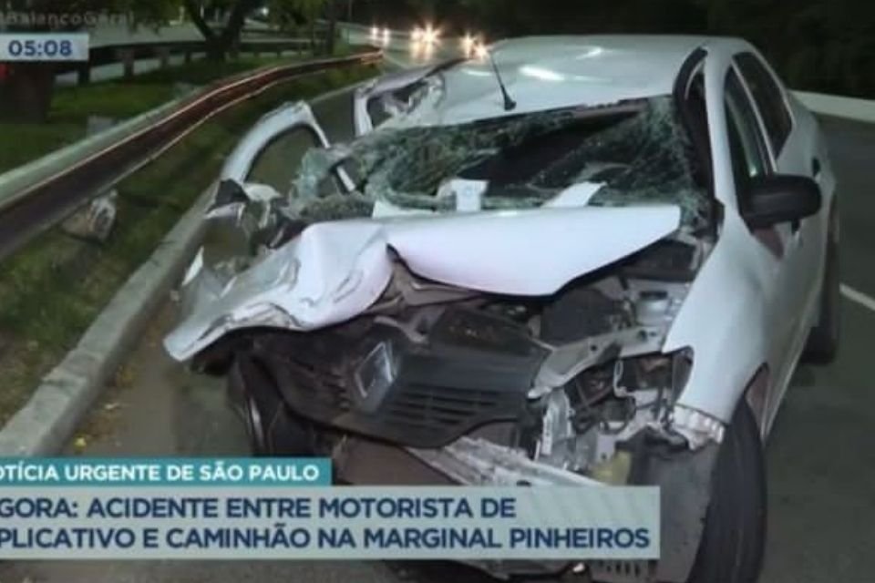 a foto colorida mostra um acidente de carro. A frente do veículo está amassada e os vidros estão quebrados