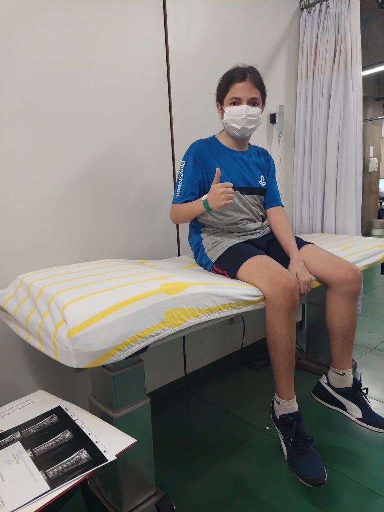 Carlos sentado na maca do hospital em uma de suas interna&ccedil;&otilde;es