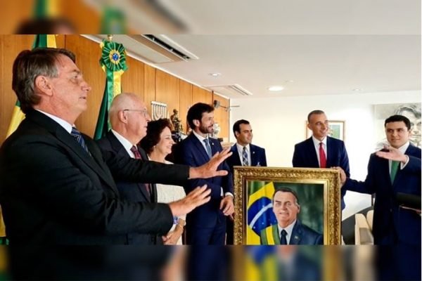 Bolsonaro recebeu os evangélicos no gabinete junto com a deputada Carla Zambelli. Na foto ele gesticula diante de um desenho seu com a faixa presidencial - Metrópoles