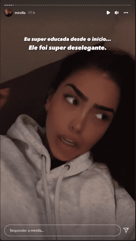 Mulher deitada em sofá, falando para a câmera, de casaco branco