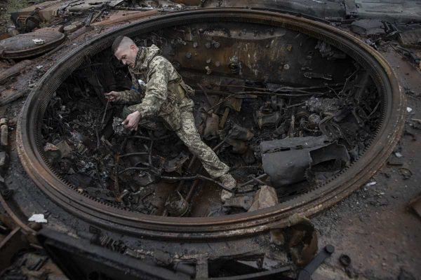 Um soldado ucraniano inspeciona um tanque russo queimado em 2 de abril de 2022 em Dmytrivka, região de Kiev, Ucrânia