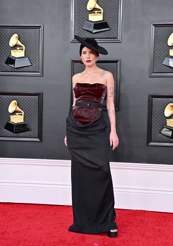 Halsey no tapete vermelho do Grammy 2022, usando vestido com corset vinho e saia preta, além de chapéu preto
