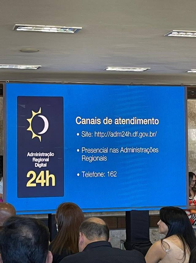 Painel azul com informações do GDF em cerimônia no Palácio do Buriti, com canais de atendimento da população com administração regional - Metrópoles