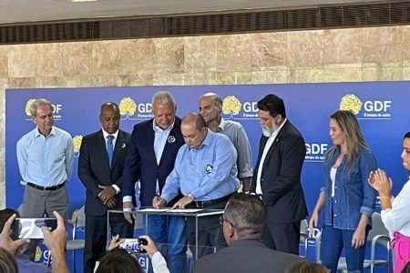 Ibaneis Rocha assinando papel com várias pessoas ao redor - Metrópoles