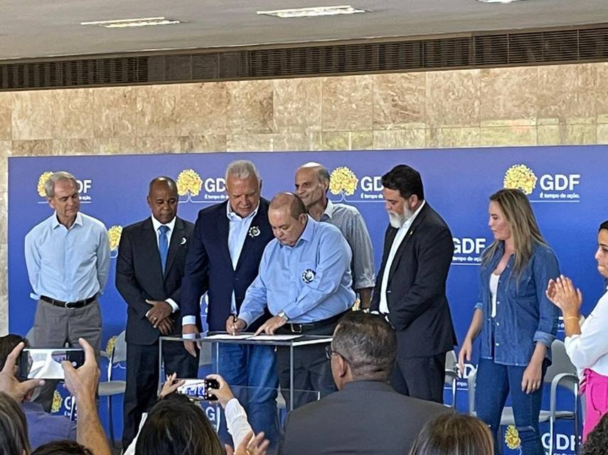 Ibaneis Rocha assinando papel com várias pessoas ao redor - Metrópoles