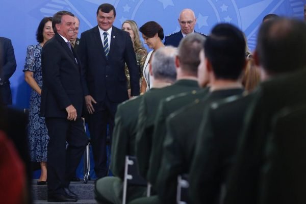 Bolsonaro convera com Paulo Sérgio Nogueira de Oliveira, general e comandante do Exército brasileiro em cerimônia de promoção de oficiais-generais. Ambos riem - Metrópoles