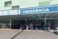 Fotografia colorida de grupo de pessoas na frente de hospital com braços cruzados