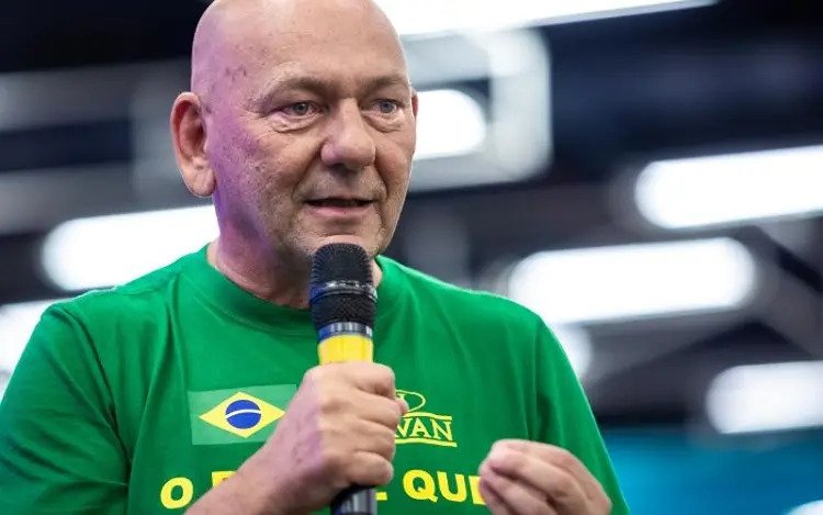 O empresário brasileiro e dono da loja Havan, Luciana Hang, fala em evento com microfone na mão. Ele usa camisa da empresa com as cores verde e amarela - Metrópoles