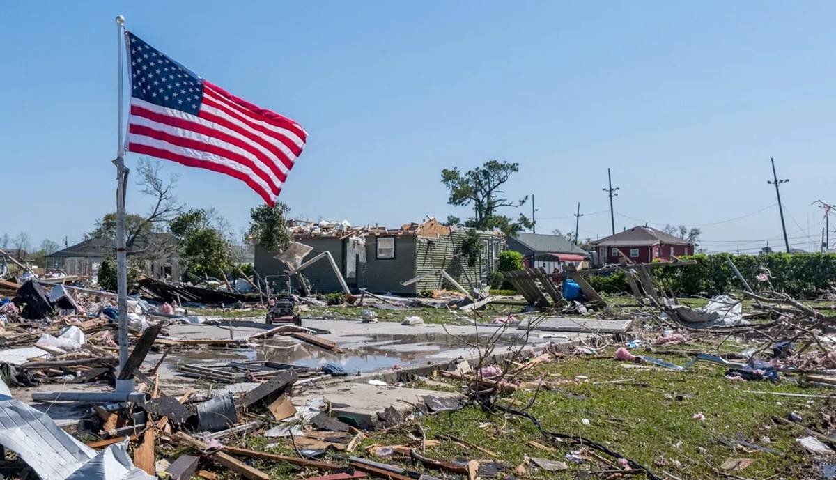 Área residencial destruída por um tornado. Logo à frente, uma bandeira dos Estados Unidos está esteada - Metrópoles