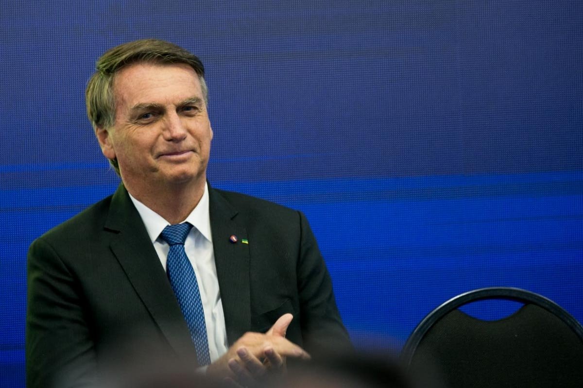 Presidente Bolsonaro participa do lançamento do programa do Banco do Brasil, Antecipa Frete. Ele está sentado e sorri para a plateia - Metrópoles