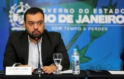 Governador do Rio de Janeiro, Cláudio Castro, fala em coletiva de imprensa. Ele usa terno e fala diante de microfone, sentado à mesa - Metrópoles