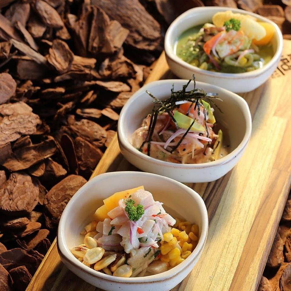 NA FOTO VEMOS UMA TABUA DE MADEIRA COM TRES CUMBUCAS COM CEVICHE