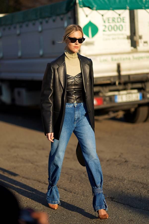 Mulher branca andando na rua com calça jeans e jaqueta de couro