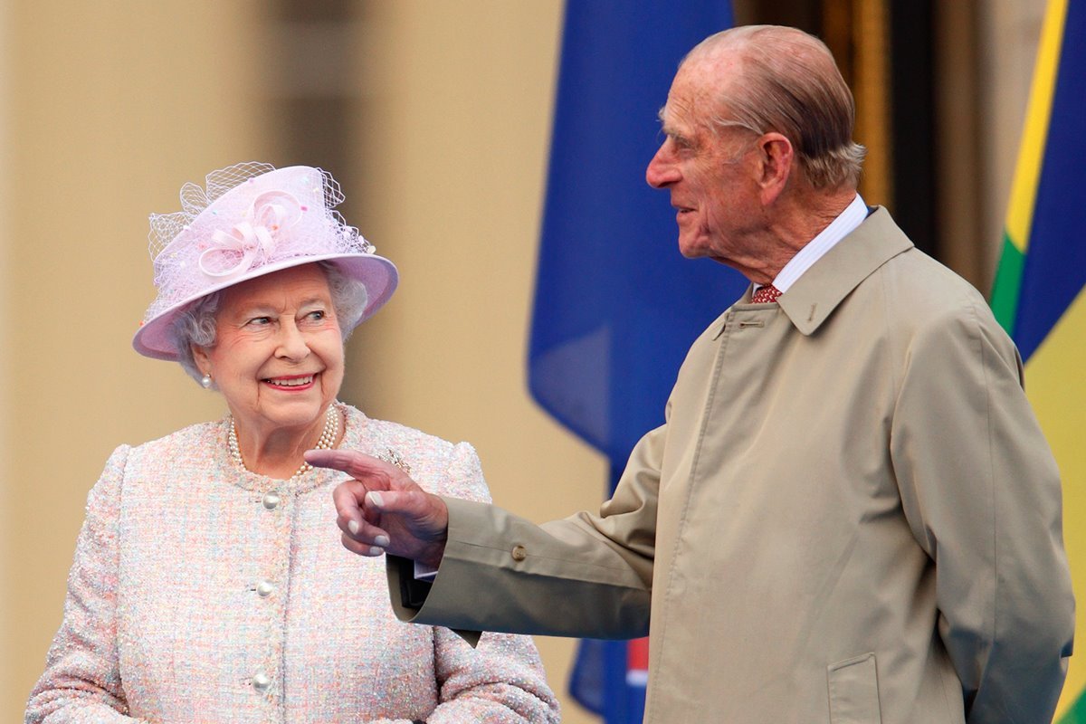 Rainha Elizabeth e seu marido príncipe Philip, que morreu em 2021. Eles usam roupas formais e conversam em evento - Metrópoles