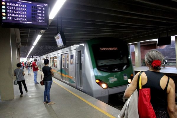 Estação do Metrô-DF sentido Samambaia onde passageiros aguardam na plataforma e um trem se aproxima rapidamente. Acima, é possível ver um painel mostrando os horários das próximas viagens - Metrópoles