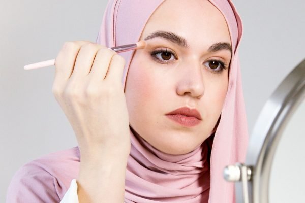 Mulher de hijab fazendo maquiagem em rosto